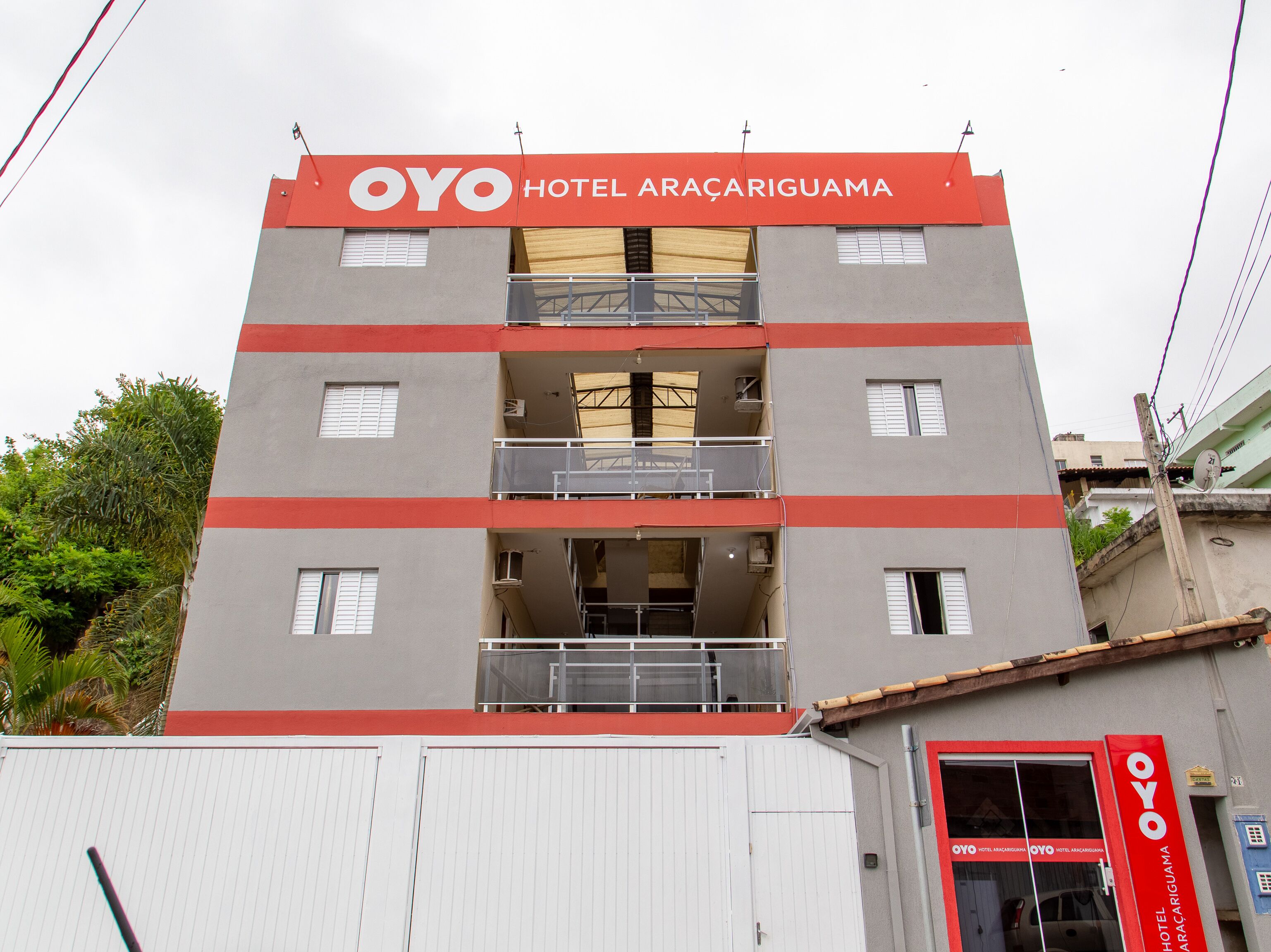 A multi-story building with a prominent red and grey facade, featuring balconies and windows.