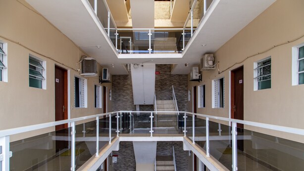 Un intérieur à plusieurs niveaux, doté de rampes en verre, d’un escalier central et offrant une vue sur l’extérieur.