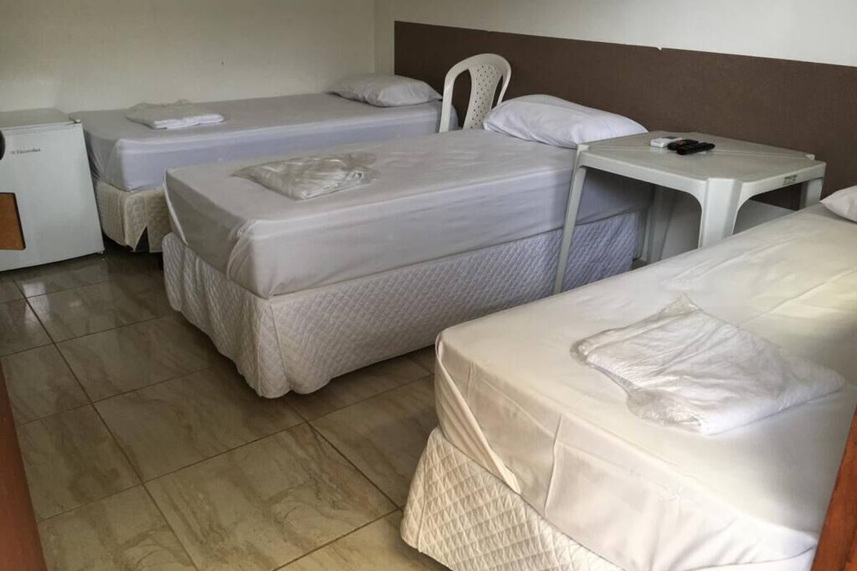 Une chambre d’hôtel avec deux lits simples, une petite table, une chaise et un bureau.