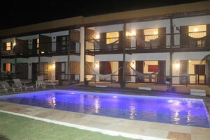 Een buitenzwembad, ligstoelen bij het zwembad