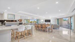 A modern kitchen with a dining area, large windows, and a TV. - Unit 41 -  3 Bed Garden View (TERRIGAL)