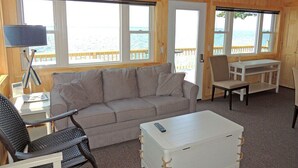 Ein gemütliches Blockhauskamin-Interieur mit einer Couch, einem kleinen Tisch, einem Stuhl und einer weißen Kommode.