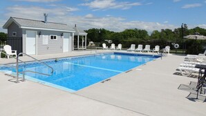 Ein Swimmingpool mit Liegestühlen und ein kleines Gebäude, vermutlich ein Umkleideraum oder Lagerraum.