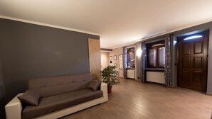Ein modernes Wohnzimmer mit einer Couch, einer Topfpflanze und Holzboden.