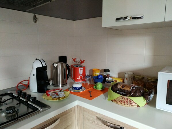 A kitchen with a gas stove, coffee maker, kettle, toaster, and various kitchen items on the counter.