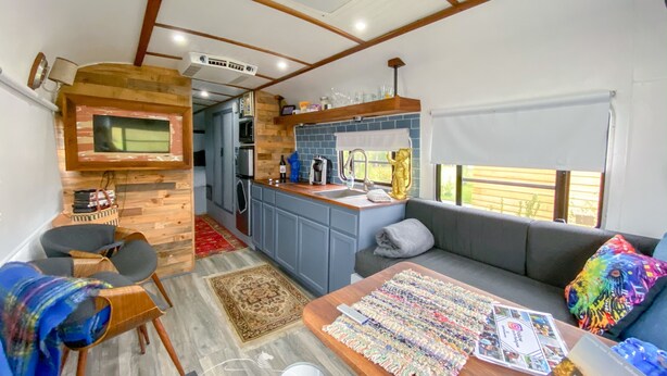 Un intérieur de camping-car compact comprenant un coin cuisine, un espace salon et une petite table à manger.