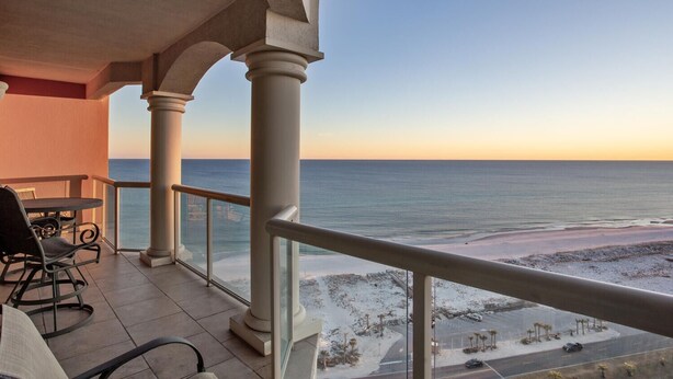 Uma varanda com vista para a praia e o oceano.