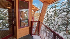 Eine Holzhütte mit einem Balkon mit Blick auf schneebedeckte Bäume.