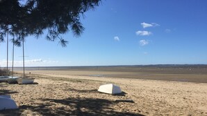 A sandy beach with a clear sky, a few boats, and a tent. - House and its pool near the beach (Andernos-les-Bains)