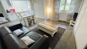 A compact living space with a sofa, a coffee table, a dining area with a table and chairs, and a television on a stand. - House and its pool near the beach (Andernos-les-Bains)