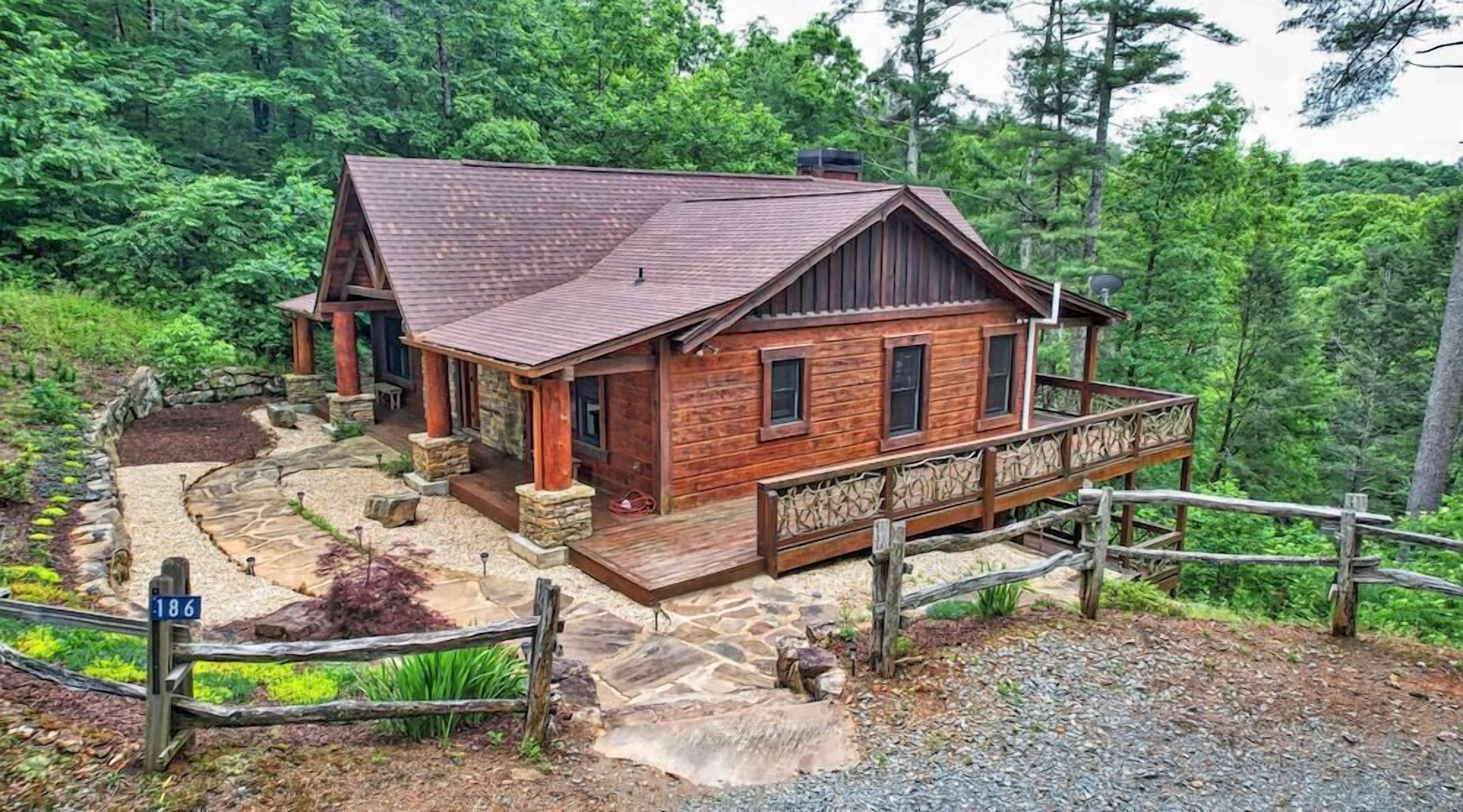 A wooden cabin with a stone foundation, a porch, and a deck.