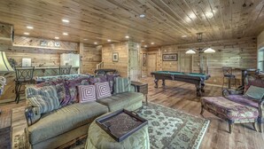 Un interior de madera con un sofá, una mesa de billar y una zona de comedor.