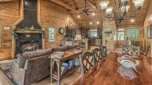 Interior acogedor de una cabaña de troncos con chimenea, muebles de madera y una zona de comedor.