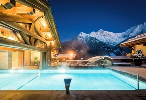 Area piscina con montagne sullo sfondo, architettura in legno e cielo notturno sereno.