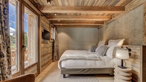 Een slaapkamer met een groot bed, een televisie en een raam met gordijnen.