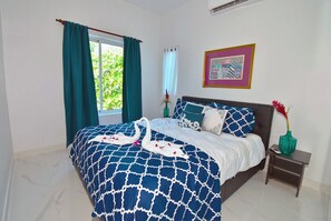 A bedroom with a bed, a nightstand, a vase, and a framed picture on the wall.