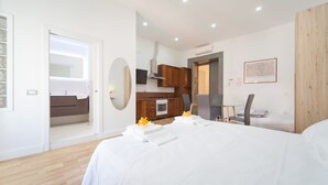 A modern hotel room with a large bed, a small kitchenette, and a bathroom with a shower and toilet. - Eugenia e Donato (Naples)