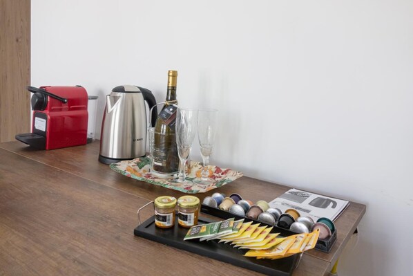 A kitchen counter with a coffee maker, a bottle of champagne, glasses, and a tray with condiments and snacks. - Eugenia e Donato (Naples)