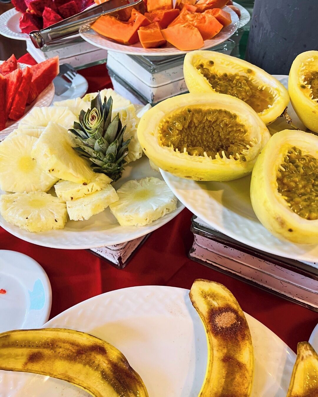 Una mesa con varias frutas, como piña, papaya y plátanos.