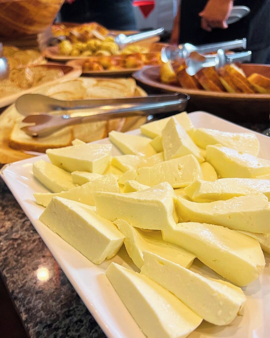 A buffet with various dishes including a plate of cubed cheese.
