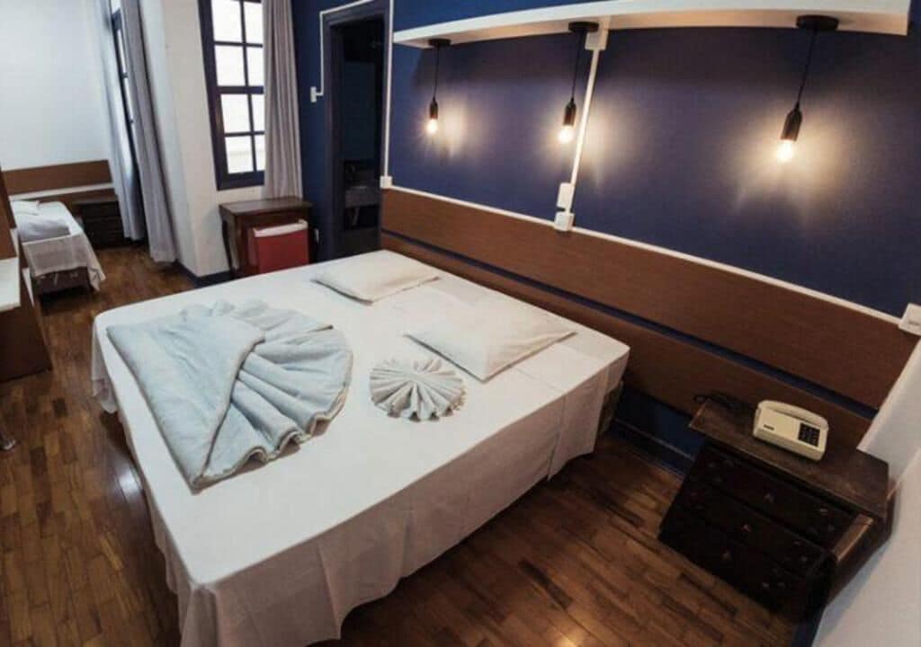 A hotel room with a large bed, bedside tables, a desk, and a telephone.