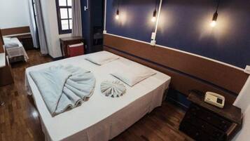 A hotel room with a large bed, bedside tables, a desk, and a telephone.