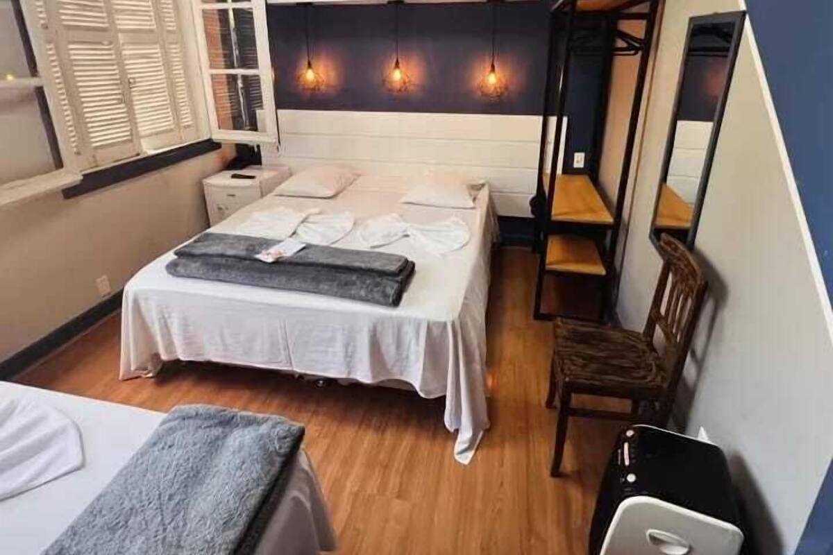 A bedroom with a bed, bedside tables, a chair, a desk, and a mirror.
