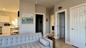Una sala de estar con un sofá gris, un ventilador de techo y piso de madera.