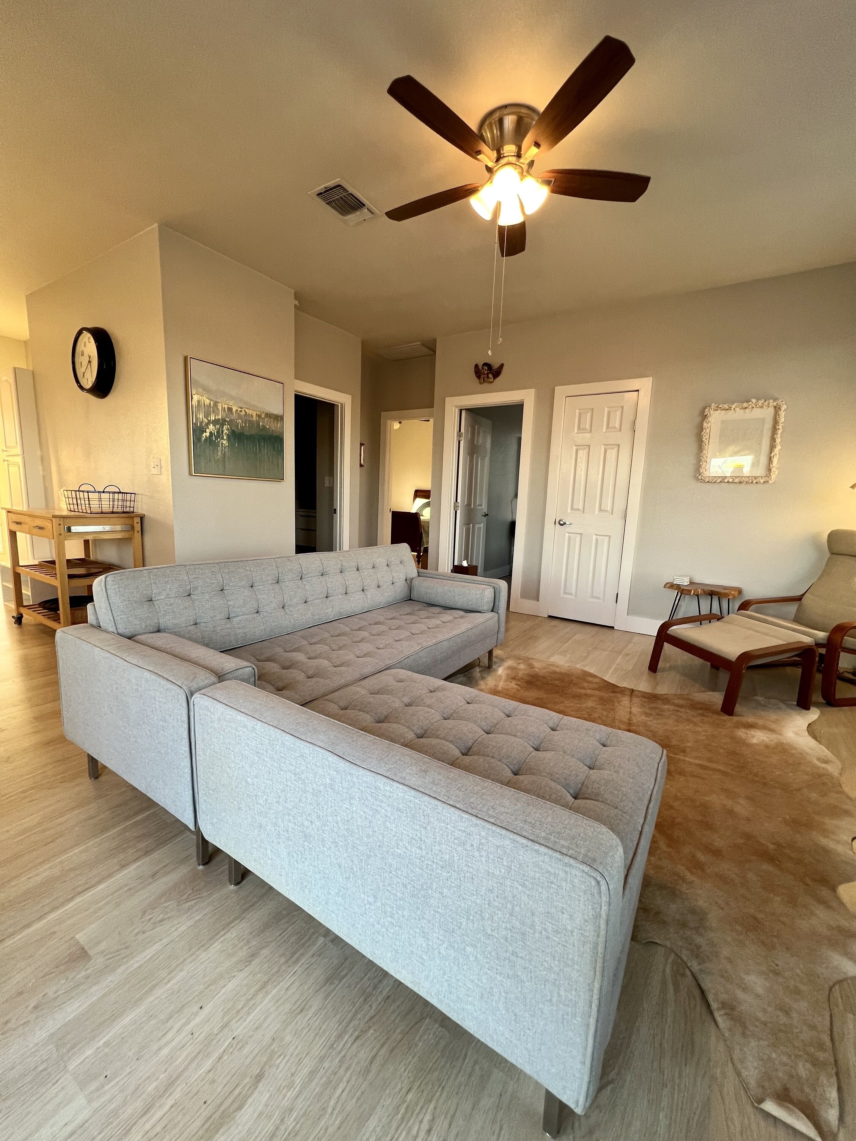 A spacious living room with a sectional sofa, a ceiling fan, a wooden coffee table, and a rug.