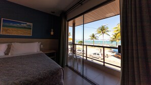 A hotel room with a large window offering a view of the beach and palm trees. - Pousada Mariluz (Maragogi)