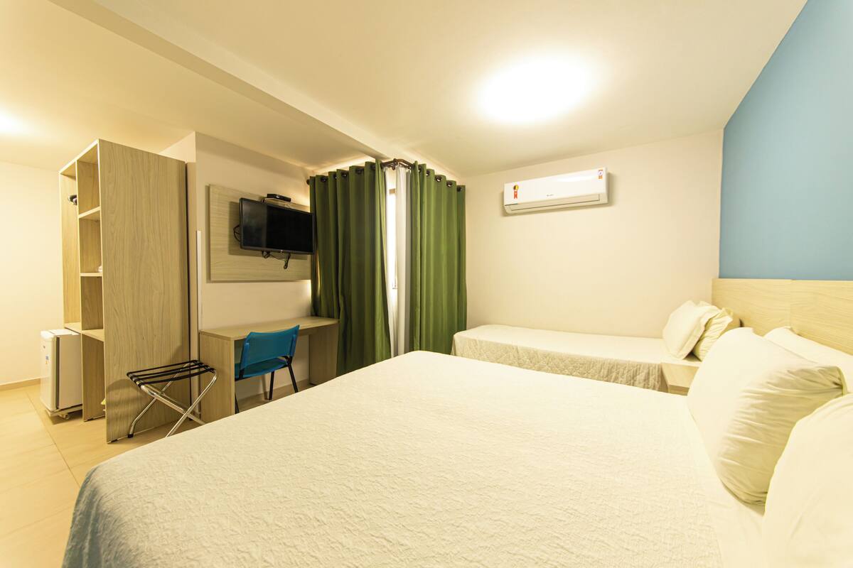 Une chambre d’hôtel avec deux lits, un bureau, une chaise et un téléviseur fixé au mur.