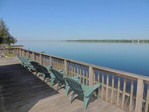 A wooden deck with green chairs facing a calm lake. - Cottage #24 - 3 bedroom/ 1 bath (Cape Vincent)