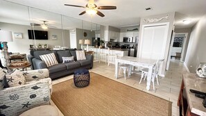 A modern living room with a grey sofa, a coffee table, and a dining area with a white table and chairs. - 🌊Walk to Beach-Balcony-Pool-Southwind I-9🌊 (Panama City Beach)