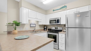A modern kitchen with white cabinets, stainless steel appliances, and a granite countertop.