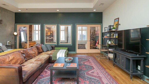 A living room with a leather sofa, a coffee table, a TV stand, and a patterned rug.