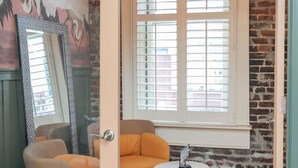 A room with a large window, a mirror, two chairs, a small table, and a decorative wall with a crane mural.