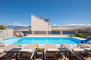 Ein Pool auf dem Dach mit Liegestühlen und Blick auf Berge.
