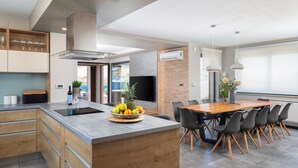 A modern kitchen with a central island, dining area with chairs, and a large window.