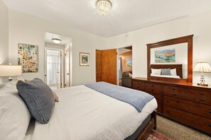 Een slaapkamer met een bed, een kaptafel en een schilderij aan de muur.