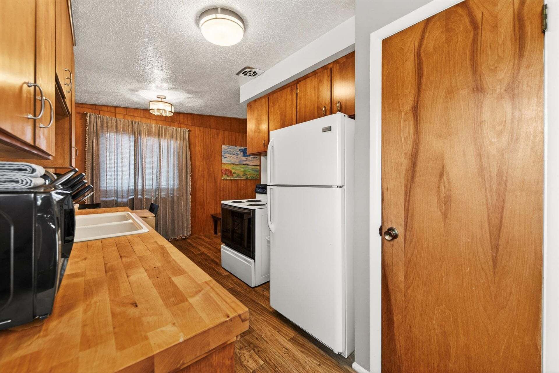 A compact kitchen with wooden cabinets, a white refrigerator, and a stove.