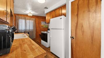 A compact kitchen with wooden cabinets, a white refrigerator, and a stove.