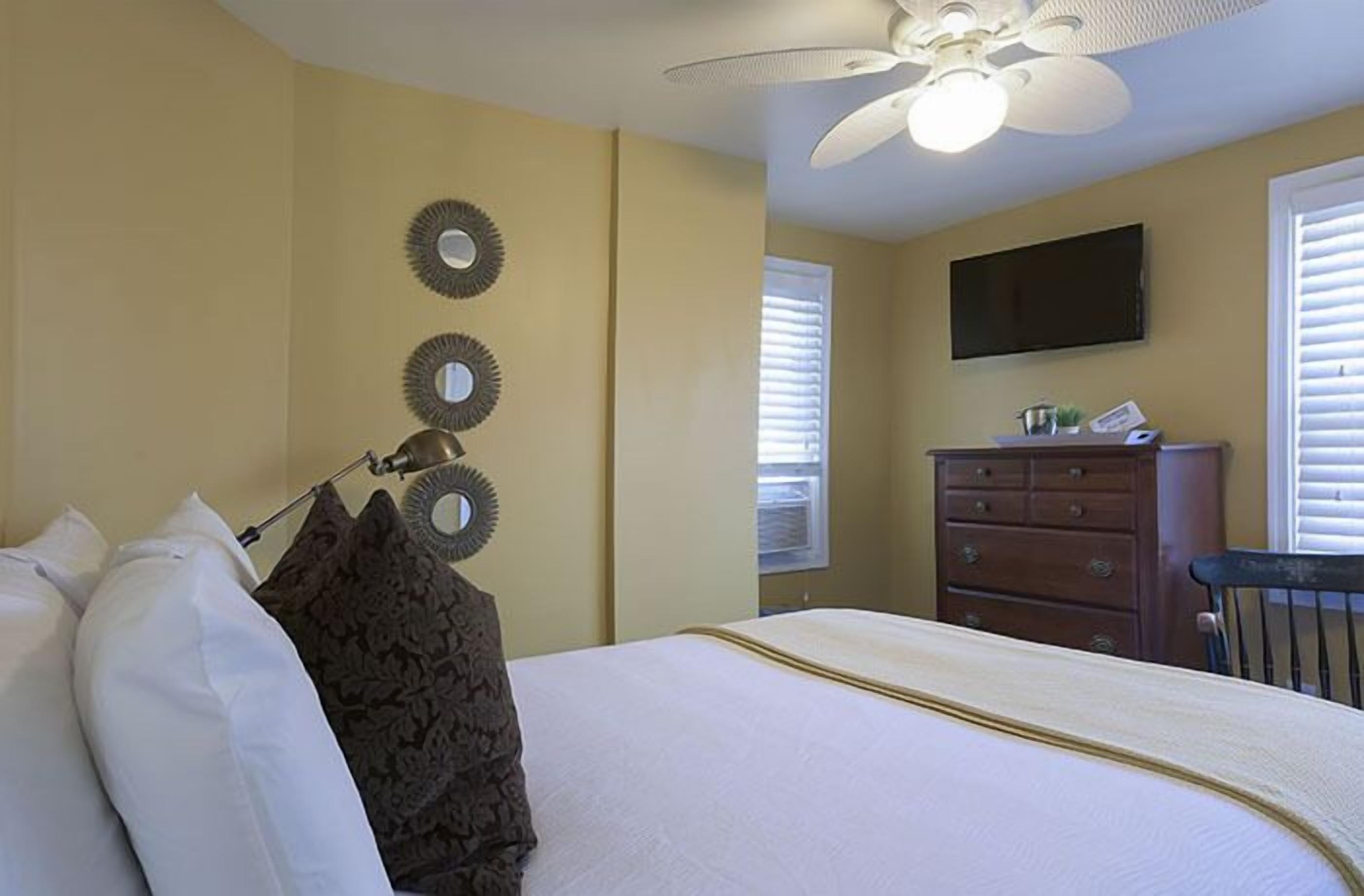 A bedroom with a bed, a dresser, a ceiling fan, and wall-mounted decor.