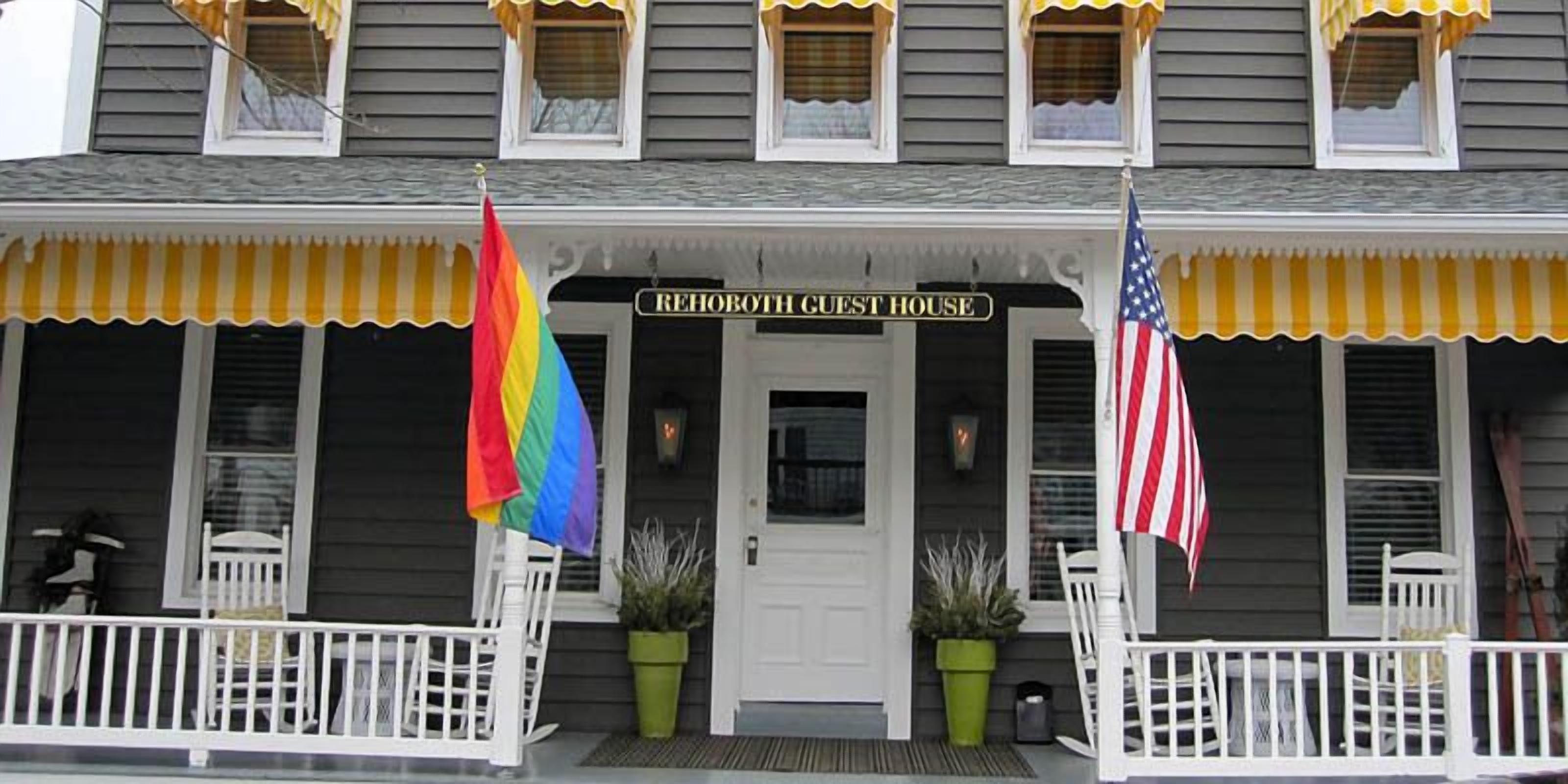 A two-story building with a porch, a sign reading "REHOBOTH GUEST HOUSE", and two flags.