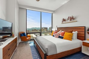 Une chambre à coucher moderne avec un grand lit, un bureau, une chaise et un téléviseur.