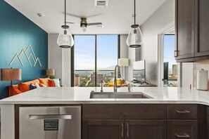 Une cuisine moderne dotée d’un grand îlot central, d’un lave-vaisselle encastré et offrant une vue sur la ville.