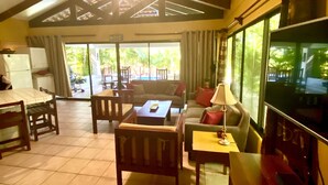 A spacious living area with a high ceiling, a television, and a view of the outdoors through large windows. - Beautiful Costa Rican Villa in Gated Beach Resort (Playa Hermosa)