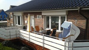 Una casa residenziale con un balcone, facciata in mattoni e tetto in tegole.