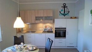 Una cucina funzionale con mobili bianchi, un tavolo da pranzo con sedie e una lampada a sospensione.