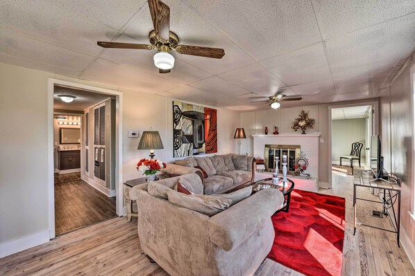 A spacious living room with a large beige sectional sofa, two ceiling fans, and a red rug.