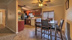 A kitchen with wooden cabinets, a dining table with chairs, a ceiling fan, and a window with blinds. - 3 Mi to Lake Powell: Page Home w/ Patio & BBQ (Page)